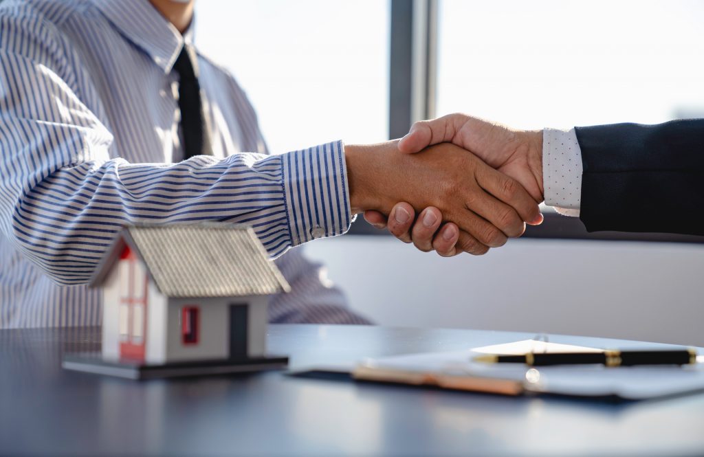 real estate businesspeople shaking hands in office for business merger teamwork successful negotiati